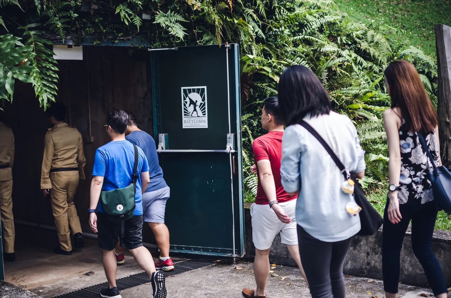 Players following a facilitator in uniform through the blast door into the Battlebox at Fort Canning