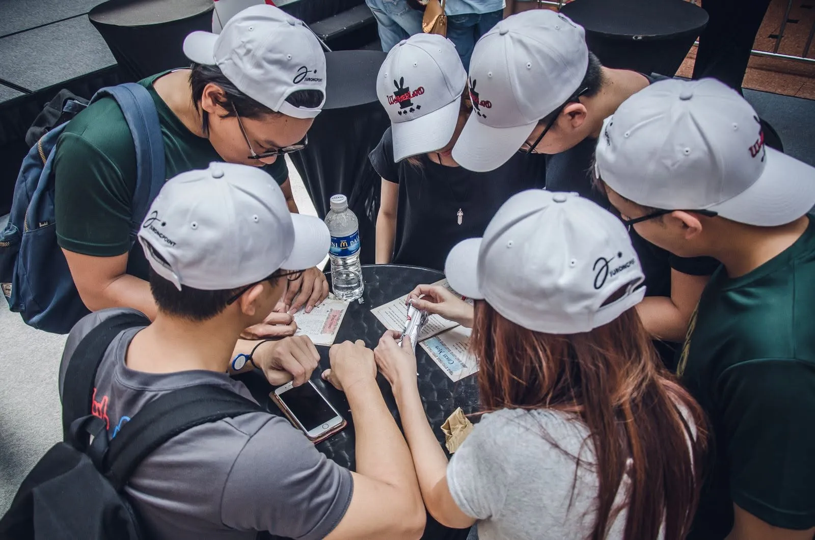 A team huddled over physical puzzle sheets during Wonderland at Vivocity